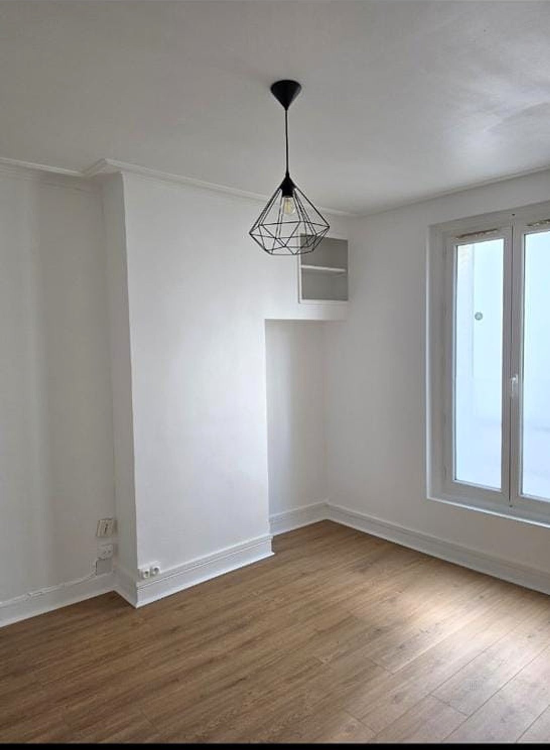 Chambre après rénovation — murs blancs, parquet neuf, luminaire design