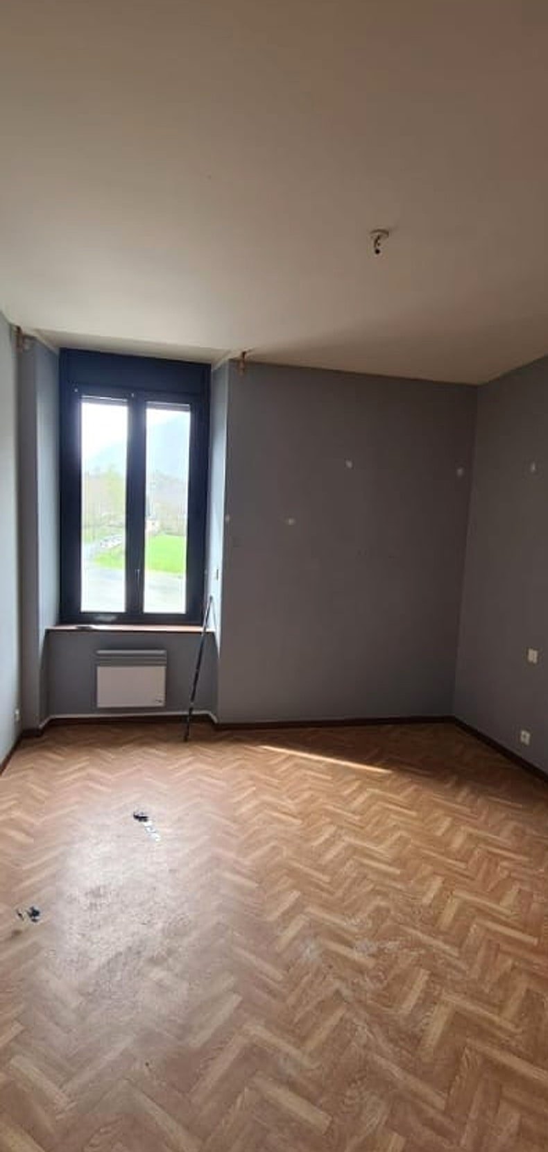 Séjour avant rénovation — sol ancien et murs gris