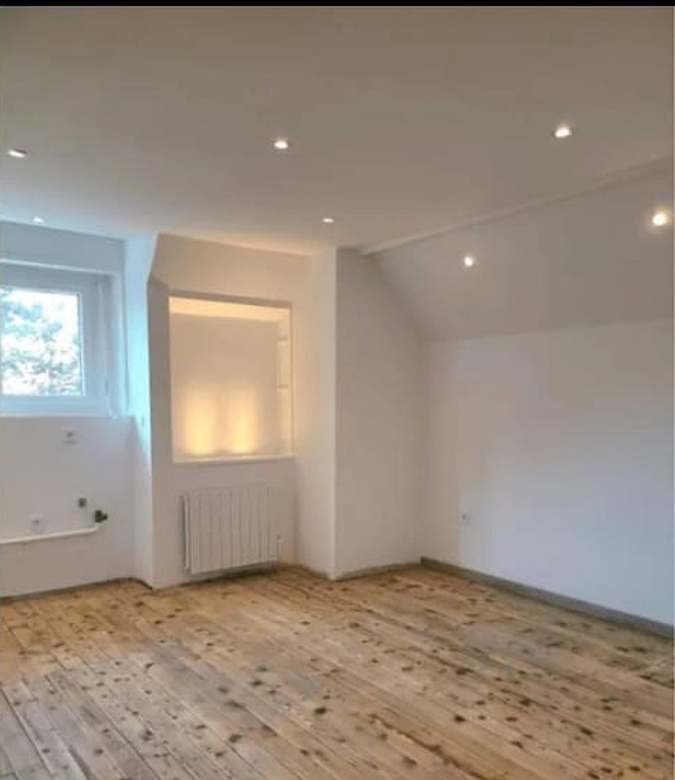 Chambre sous combles après rénovation — parquet bois, murs blancs, spots encastrés